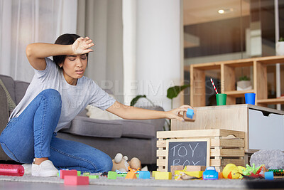 Buy stock photo Toys, mother tired and headache for cleaning, messy living room and exhausted. Woman, clean playthings and female stress, frustrated and upset in lounge, annoyed and overworked in home with disorder.