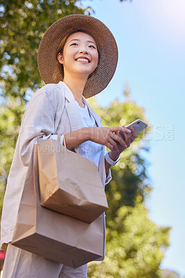 Buy stock photo Phone, asian woman and shopping bag with happy, smile and technology with web outdoor. Happy young person texting, internet networking and doing a social media app scroll online with happiness