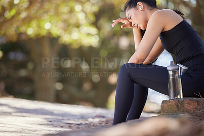 Buy stock photo Fitness, tired and woman runner in a park taking a water break in nature to listen to radio or music. Exercise, rest and girl sweat to breathe while listening to a podcast for wellness and training 