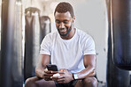 Fitness, music and phone with black man in gym for training, workout and exercise. Social media, streaming and internet with bodybuilder relax with mobile in sports center for health and performance