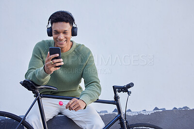Buy stock photo Black man, bicycle and headphones for travel, social media update and 5g networking on nature or sky mockup for marketing. Student bike, music streaming service and smartphone with advertising space