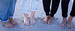 Beach feet, friends and people on vacation, holiday or summer trip. Toes, freedom and group of men and women standing on sandy seashore, seaside or coast, having fun or enjoying quality time outdoors