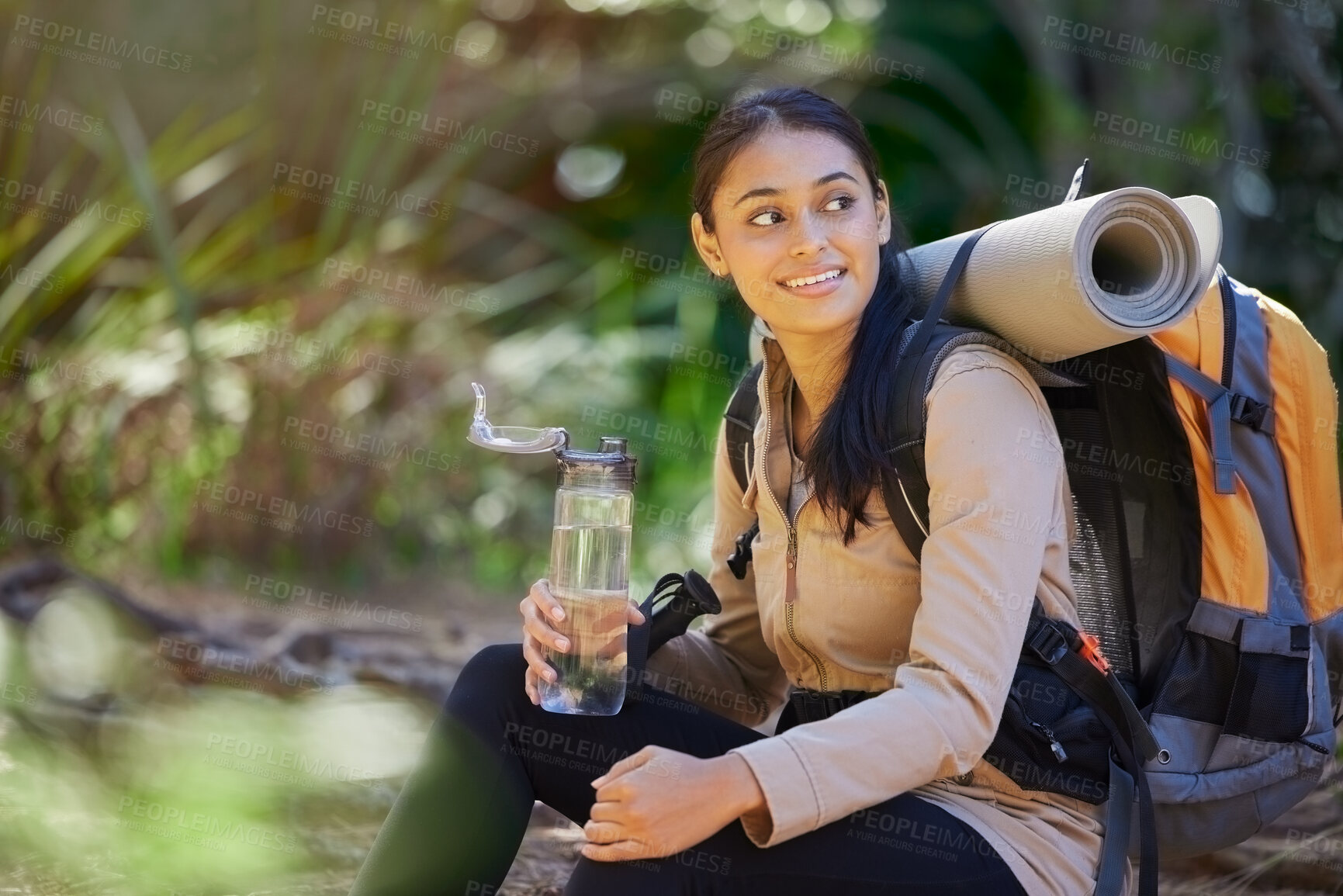 Buy stock photo Drinking water, hiking and backpack with an indian woman in nature for exercise or a recreation hobby. Fitness, forest and workout with a young female taking a break to relax during a hike outdoor