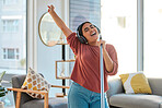 Music, headphones and woman singing while cleaning home, dancing and having fun. Singer, dance and female spring cleaning for hygiene holding broom like microphone, sweeping dust and streaming radio.
