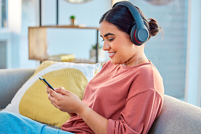 Buy stock photo Indian woman, music headphones and smartphone in living room for social media app, radio podcast and ebook listening on sofa. Young girl, mobile audio streaming and watch web with technology at home