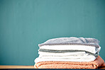 Bathroom, laundry and stack of towels on blue background for cleaning, washing and body hygiene at home. Fabric, textiles and pile of fresh, soft and clean linen for shower, bath and spa wellness