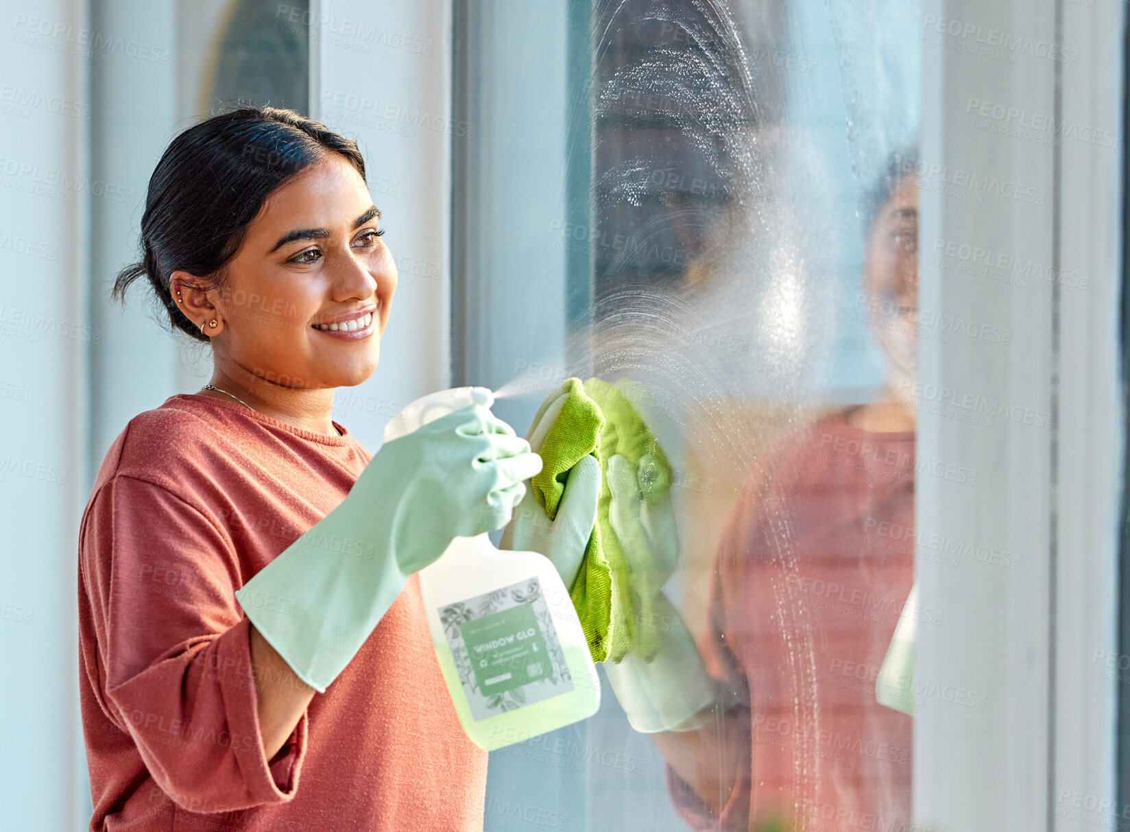 Buy stock photo Glass, spray or woman cleaning a window with liquid soap or chemical product for dusty bacteria or germs at home. Cleaning services, dirty or happy Indian girl cleaner washing glass door with a cloth