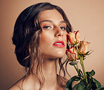 Beauty, flowers and face of woman in studio for wellness, fashion and skincare on brown background. Makeup, cosmetics and female model with roses for beauty salon, natural self care and spa aesthetic