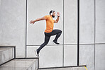 Fitness, running and man with headphone on stairs for exercise, workout and wellness, body goals and health on music app. Sports, athlete or runner jump or run listening to audio and training in city