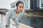 Headphones, fitness and runner woman on a urban street with motivation, music and exercise. City run, sport and marathon training workout of a black woman athlete listening to web radio for sports