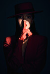 Fashion, silence and woman in red suit on a dark studio background. Quiet, spotlight and face portrait of beautiful, vintage or 90s female model in makeup cosmetics with shush hand gesture for peace.