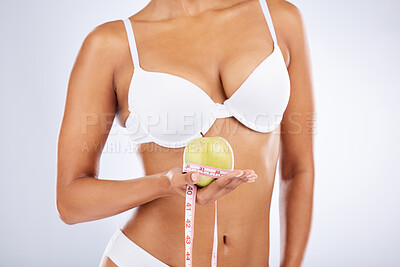 Buy stock photo Apple, tape and woman underwear in studio with diet, lose weight results and body goals for wellness, healthcare and nutrition. Fruit, nutritionist and model in lingerie with gut health and digestion