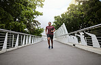 Running, bridge and black man athlete training for marathon run, wellness and sports. Speed cardio, runner workout and fitness workout of a man doing health exercise on a urban road in the morning