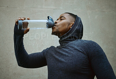 Buy stock photo Black man, running and drinking water for health and wellness during exercise, workout and cardio training with hood. Face of athlete male with sports bottle for hydration during urban fitness run