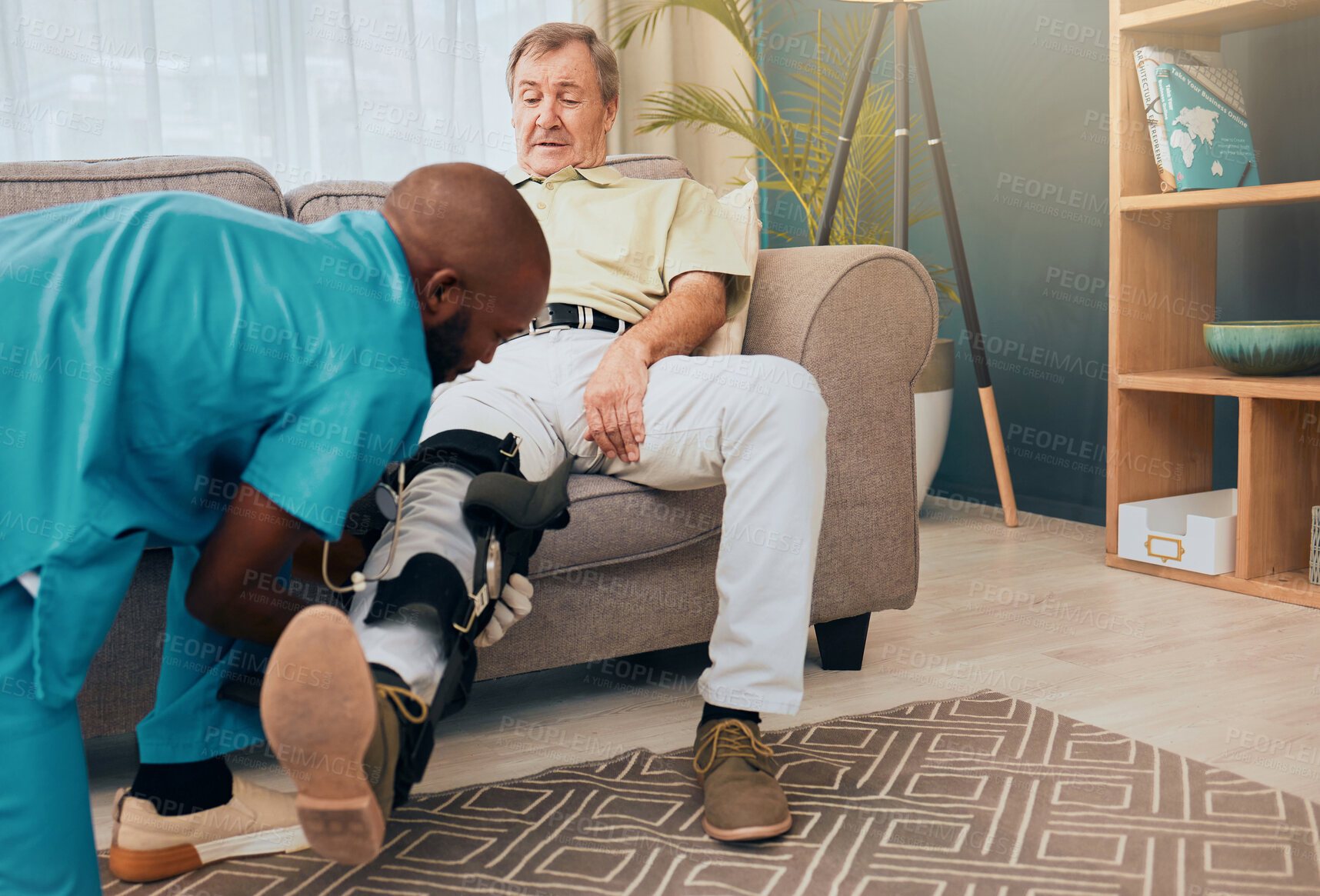 Buy stock photo Senior man, physiotherapist and leg brace for rehabilitation, injury and support for wellness, muscle or knee. Man, sofa and physiotherapy with nurse, doctor or caregiver for health, training or talk