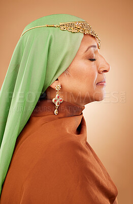 Buy stock photo Muslim, culture clothes and senior woman with jewelry, faith and hijab against a brown studio background. Islamic fashion, traditional and modest burka model with religion, spiritual and scarf