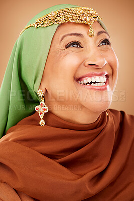 Buy stock photo Fashion, beauty and muslim woman with culture jewelry and head scarf posing with a smile in a studio. Tradition, arabic and mature indian lady with hijab and jewellery isolated by a brown background.
