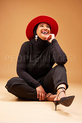 Buy stock photo Fashion, beauty and muslim woman in hat in studio on a brown background. Vintage aesthetic, mature or Islamic female model laughing, sitting on floor and thinking of classy, stylish or retro clothing