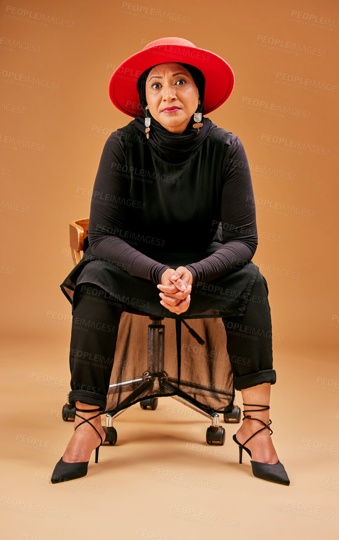 Buy stock photo Fashion, beauty and senior woman on chair in studio on brown background with stylish, cool and trendy outfit. Creative art, style and Muslim female model with designer clothes and luxury accessories