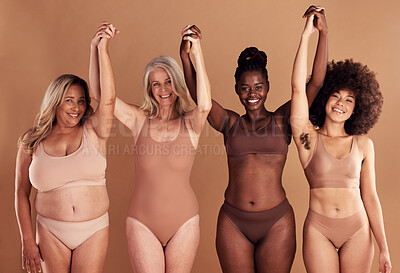 Buy stock photo Beauty, diversity and natural with woman friends in studio on a beige background with their hands raised in celebration. Wellness, underwear and real with a model female group standing together