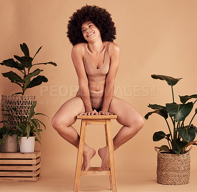 Buy stock photo African woman, lingerie and studio with smile, stool and plants for natural material underwear. Black woman, happy and sustainable cotton fabric with leaves, self love and beauty by beige background