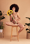 Flowers, happy and black woman in underwear for body positivity, empowerment and confidence against a brown studio background. Smile, aesthetic and portrait of a model with sunflower for skincare