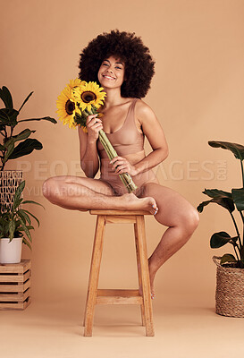 Buy stock photo Flowers, happy and black woman in underwear for body positivity, empowerment and confidence against a brown studio background. Smile, aesthetic and portrait of a model with sunflower for skincare