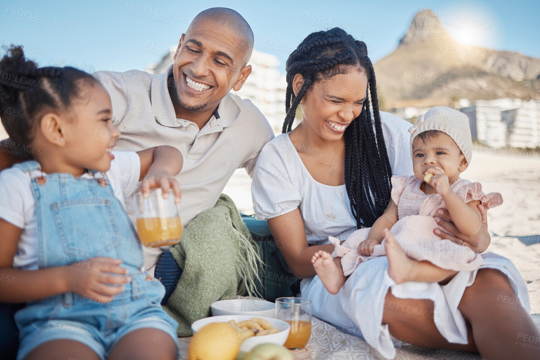 Buy stock photo Black family, happy and food picnic on beach with kids to enjoy summer outing together in Cape Town, South Africa. Children, mother and dad relax on sand in nature for bonding in sunshine.