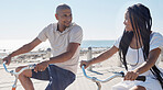 Couple, bike and beach for fun bonding in a happy, loving relationship in Cape Town, Sea Point. Cycling, fitness and bond with a man and woman riding bicycles by the seaside or ocean in summer 