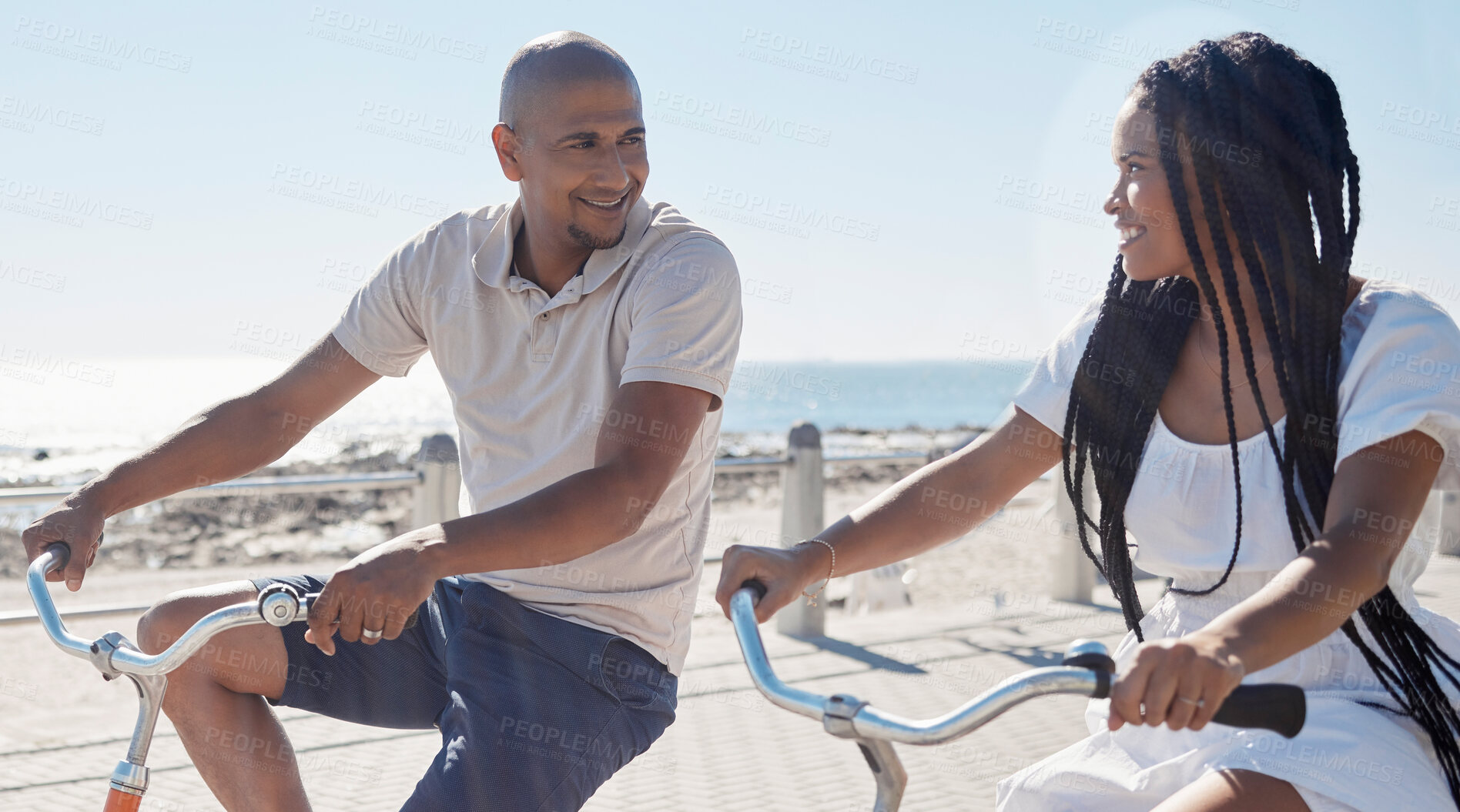 Buy stock photo Couple, bike and beach for fun bonding in a happy, loving relationship in Cape Town, Sea Point. Cycling, fitness and bond with a man and woman riding bicycles by the seaside or ocean in summer 