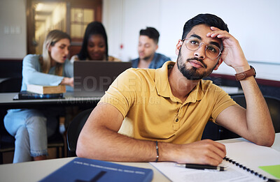Buy stock photo Indian man, student and bored in classroom, tired and stress with notes, examination or task. Young male, guy or exhausted for education, test or notes for assignment with headache and depressed