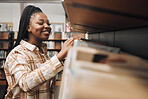 Student, checking or library bookshelf on school, college or university campus for education, learning or studying. Smile, happy or excited black woman in textbook search, research or retail shopping