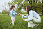 Family, park and flower with a mother and girl child bonding together on a grass field during summer or spring. Nature, love and children with a woman and female kid spending time outdoor on holiday