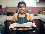 Baking, cookies and children with an indian girl cooking baked goods in the kitchen of her home alone. Food, kids and apron with a female child learning how to bake in her house in the morning