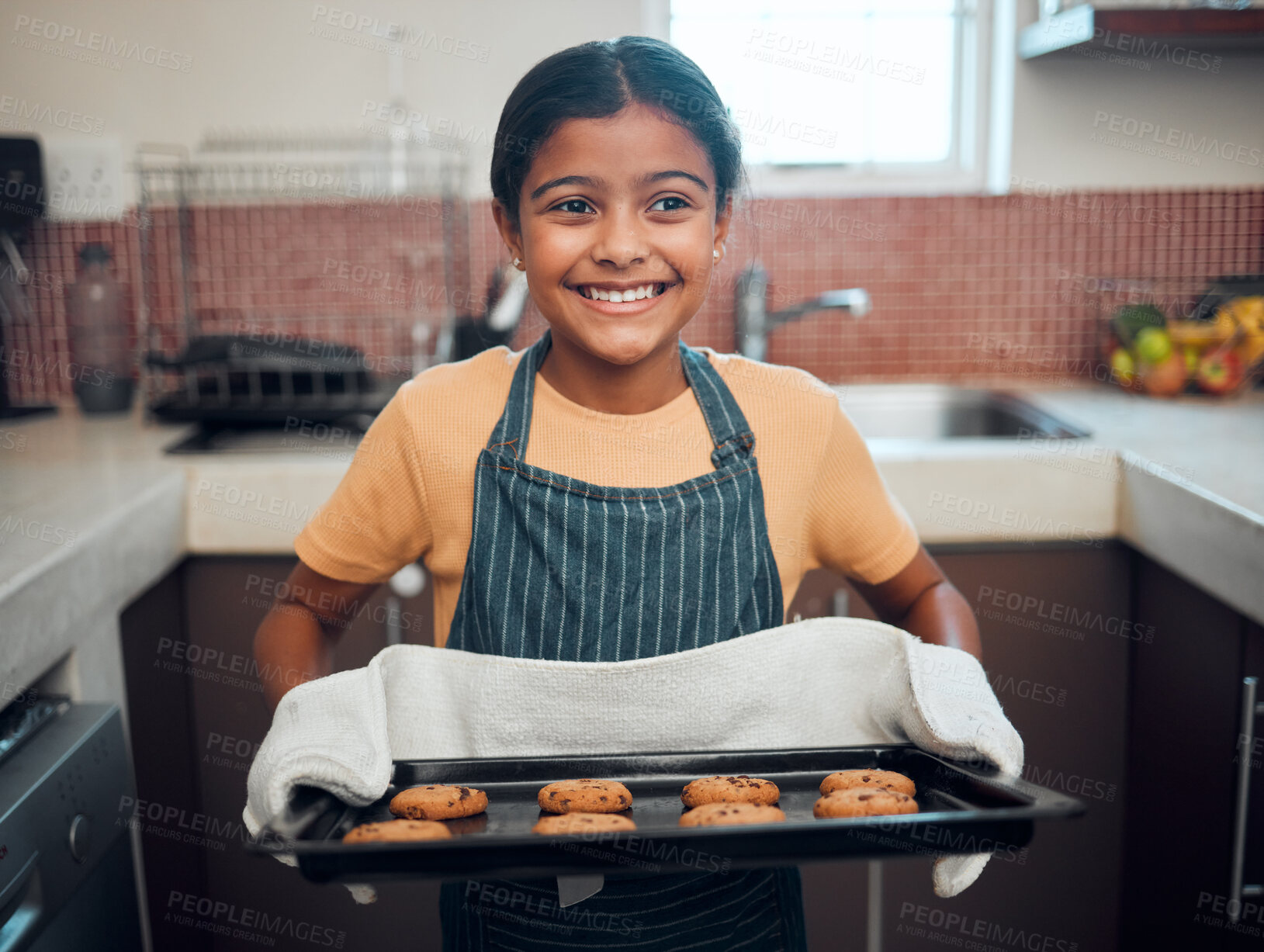 Buy stock photo Baking, cookies and children with an indian girl cooking baked goods in the kitchen of her home alone. Food, kids and apron with a female child learning how to bake in her house in the morning