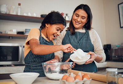 Buy stock photo Baking, family and children with a mother and daughter learning about cooking in the kitchen of their home. Food, kids and help with a girl and woman teaching her child how to bake with eggs or flour