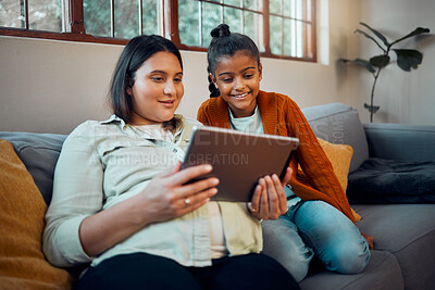 Family, video game and online gaming on home sofa with a pregnant mother  and daughter on a living room couch together while happy and having fun.  Woman and girl kid together for