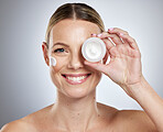 Face, skincare and product with a model woman holding a beauty container in studio on a gray background. Portrait, facial and cosmetics with an attractive young female holding moisturizer or lotion