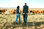 Cow, countryside or couple on agriculture farm harvesting healthy organic livestock for growth sustainability. Back view, partnership or woman farming cows or cattle with farmer on natural grass land