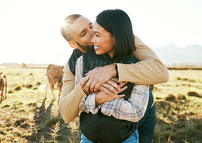 Buy stock photo Cow farm, love and couple kiss in the countryside relax on a sustainability farm with cows. Interracial happy couple, summer and marriage smile of people with a hug in nature on a grass field 