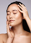 Asian, health and skincare face of model for natural facial and body care glow cosmetics campaign. Aesthetic, wellness and beauty of woman touching healthy, clean and hydrated skin in gray studio.