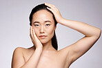 Skincare, portrait and Asian woman with cosmetics, shine and confident on grey studio background. Female, girl and makeup for healthy, soft and smooth skin, treatment or organic facial for wellness.