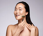 Jade roller, face massage and woman with skincare marketing, dermatology beauty and spa glow on a grey studio background. Facial, cosmetics and portrait of an Asian model with a massaging product