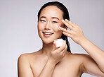 Woman, face or skincare glow with cream on studio background in dermatology wellness, collagen healthcare or Japanese grooming. Portrait, smile or happy beauty model with facial sunscreen or retinol