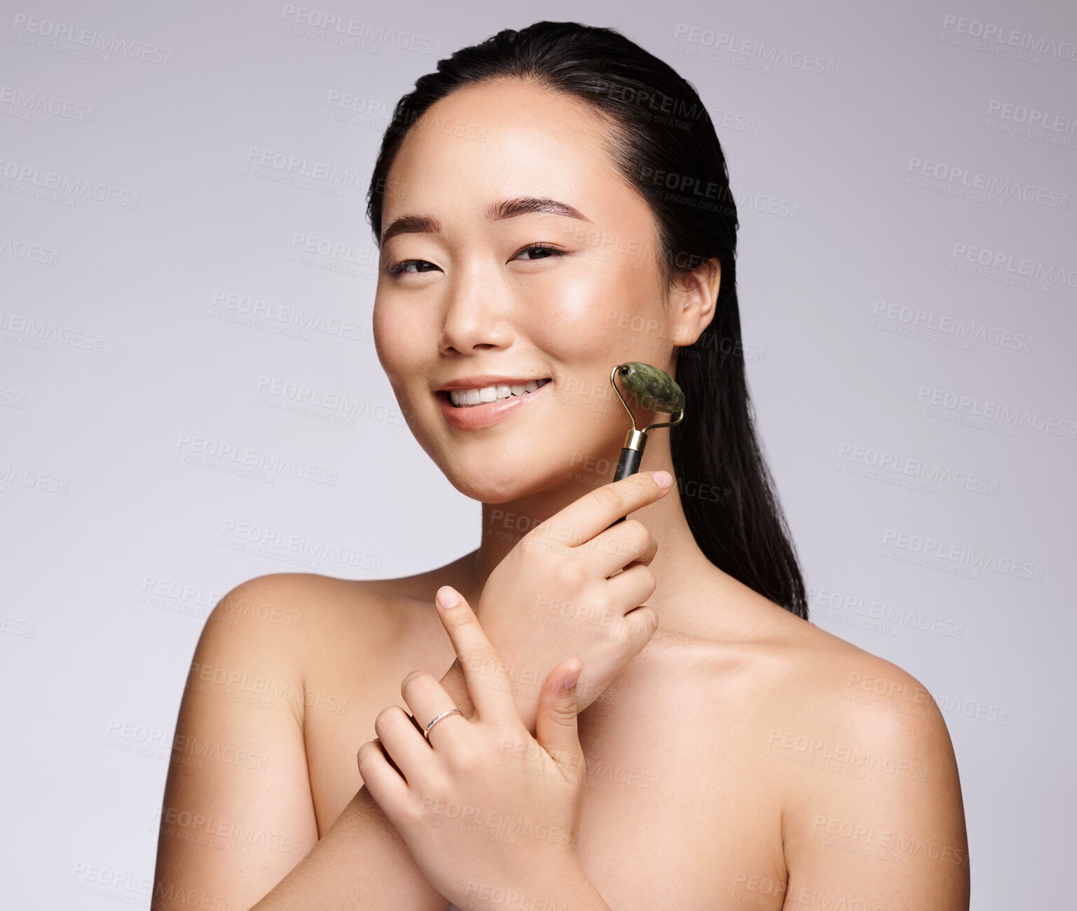 Buy stock photo Facial roller, skincare and portrait of an Asian woman in studio with a beauty, organic and natural routine. Happy, smile and girl model with face massage product for dermatology, health and wellness