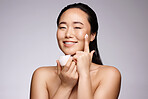 Skincare, cream and woman with beauty smile, spa cosmetics and wellness on a grey studio background. Cosmetic, luxury and face portrait of an Asian model advertising a lotion or sunscreen product
