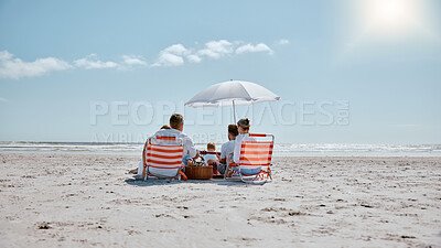 Buy stock photo Family, relax and picnic in the sun on the beach for summer vacation, holiday or weekend getaway in the outdoors. People relaxing by the ocean coast with chairs and umbrella for free time in nature