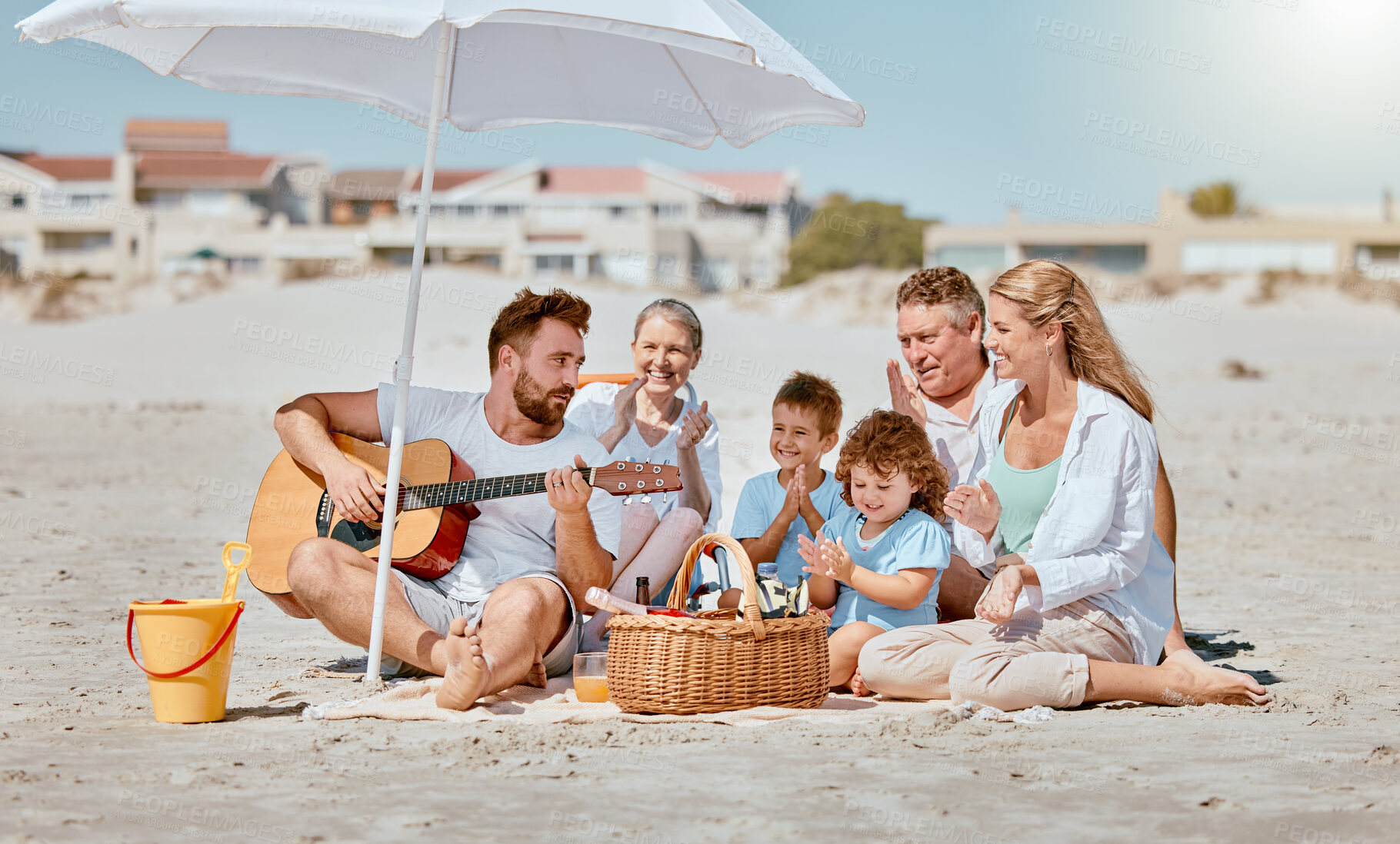 Buy stock photo Beach picnic, guitar and big family on holiday for travel, relax and music entertainment in Portugal. Happy, enjoyment and cheerful man with instrument for children, mother and senior parents