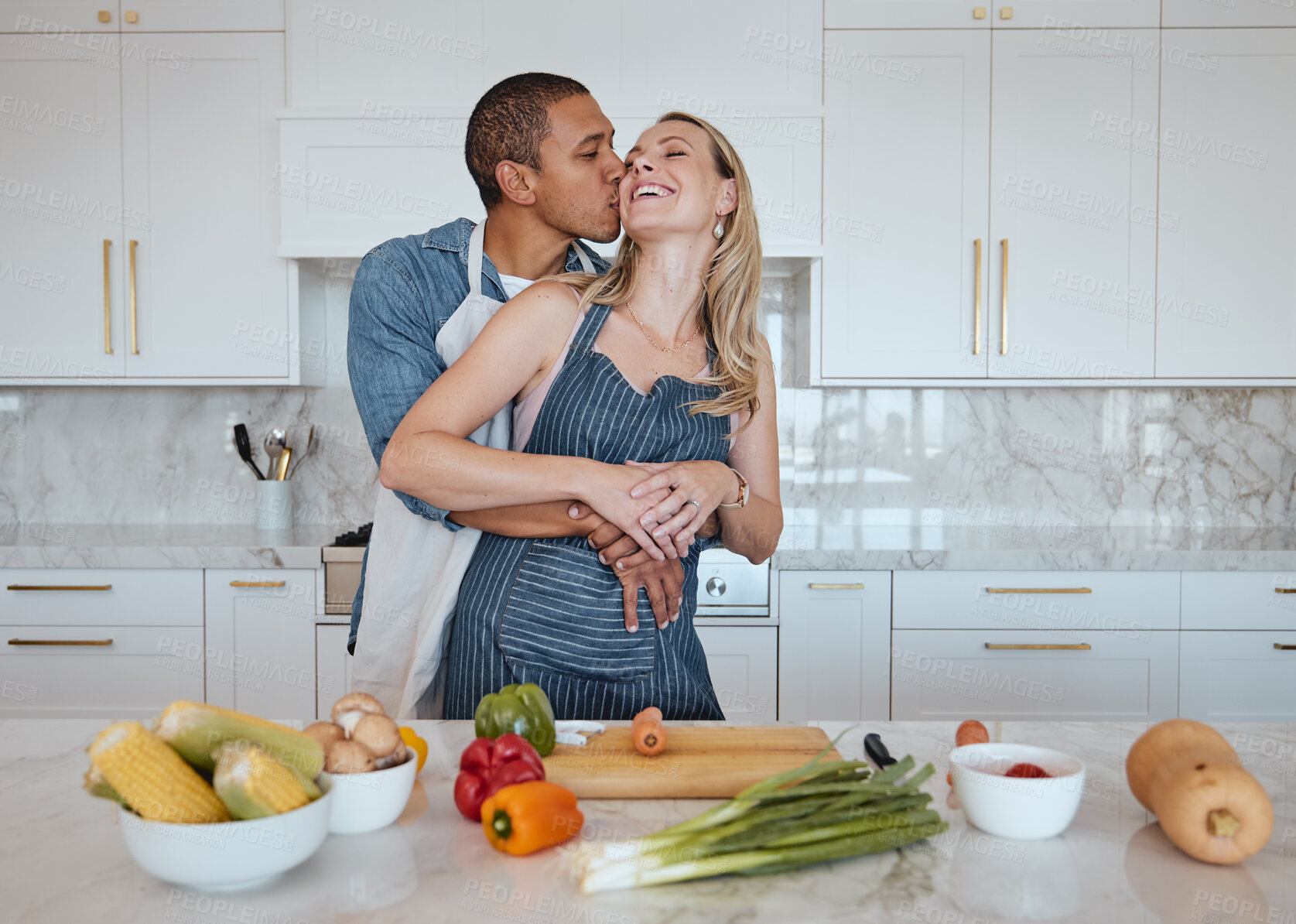 Buy stock photo Couple, cooking food and love of vegetables with a kiss on the cheek while helping with dinner at home. Man and woman in Uk with a healthy lifestyle, diet and vegan eating for health and wellness