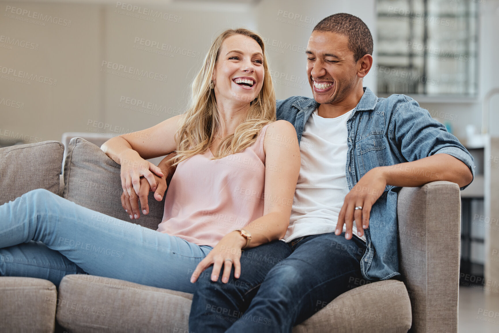 Buy stock photo Relax, funny or couple of friends love laughing at joke, story or gossip for entertainment on sofa at home. Interracial, comic or happy woman enjoying quality bonding time and holding hands with man